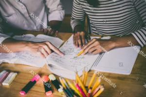 Two students doing homework while using pencils and highlighters